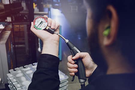 A man measuring the SILVENT Pro One air blow gun with an OSHA gauge to ensure safety compliance.