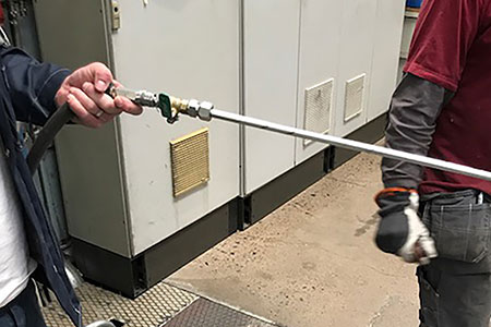 A person holding a homemade solution featuring an open pipe connected to a ball valve.