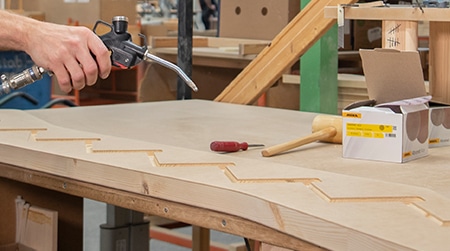 在制造木楼梯过程中，使用吹气枪清除锯末。