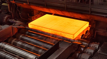 工厂里发出橘红色光的热金属片，周围是工业背景