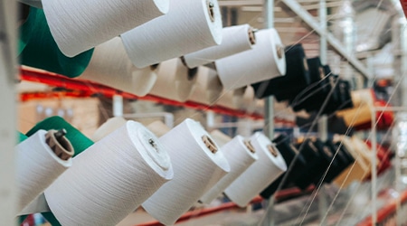 纺织厂内，多轴线团和成排的设备整齐排列。